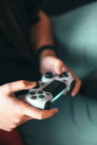 Close-up of a young adult's hands holding a video game controller.