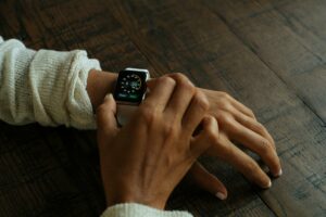 A close-up image of a young adult's hands. The young adult is wearing a smart watch.