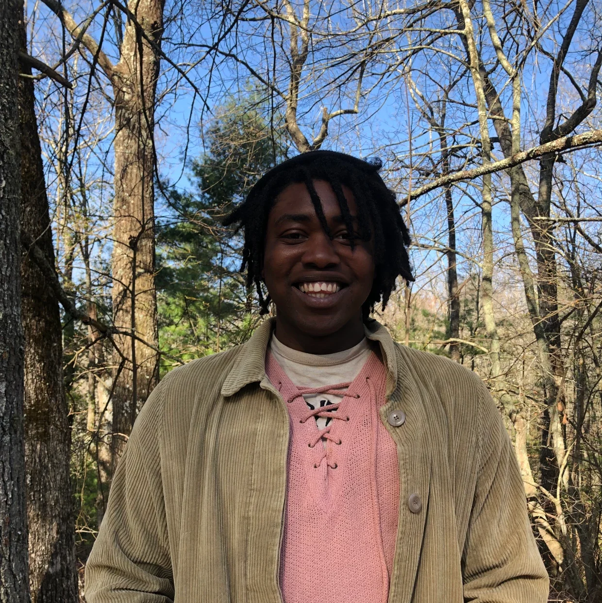 D Davis smiling and standing in front of trees and bright blue sky.